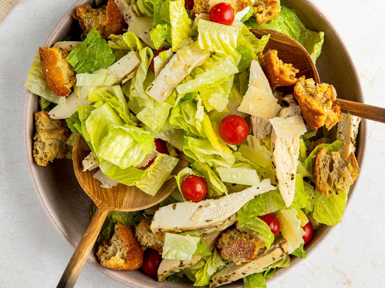Two salad spoons used to mix sheet pan caesar salad