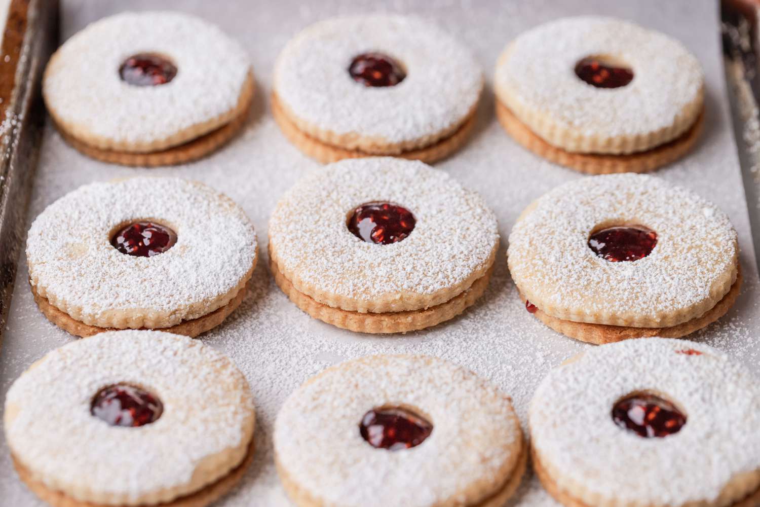 Classic linzer cookies set side by side on a baking sheet.