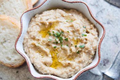 Babaganoush recipe (eggplant dip) overhead shot in a shallow bowl with bread alongside and garnished with chives.