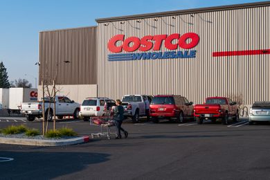 Person pushing a shopping cart in the parking lot of a Costco store