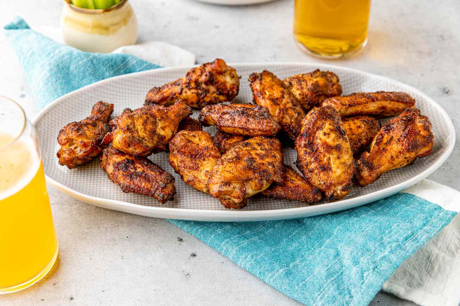 Smoked Chicken Wings on Plate on Top of Cloth Napkin and Next to Drinks