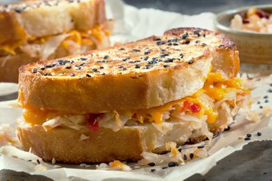 Grilled cheese sandwich filled with kimchi and melted cheese sprinkled with sesame seeds