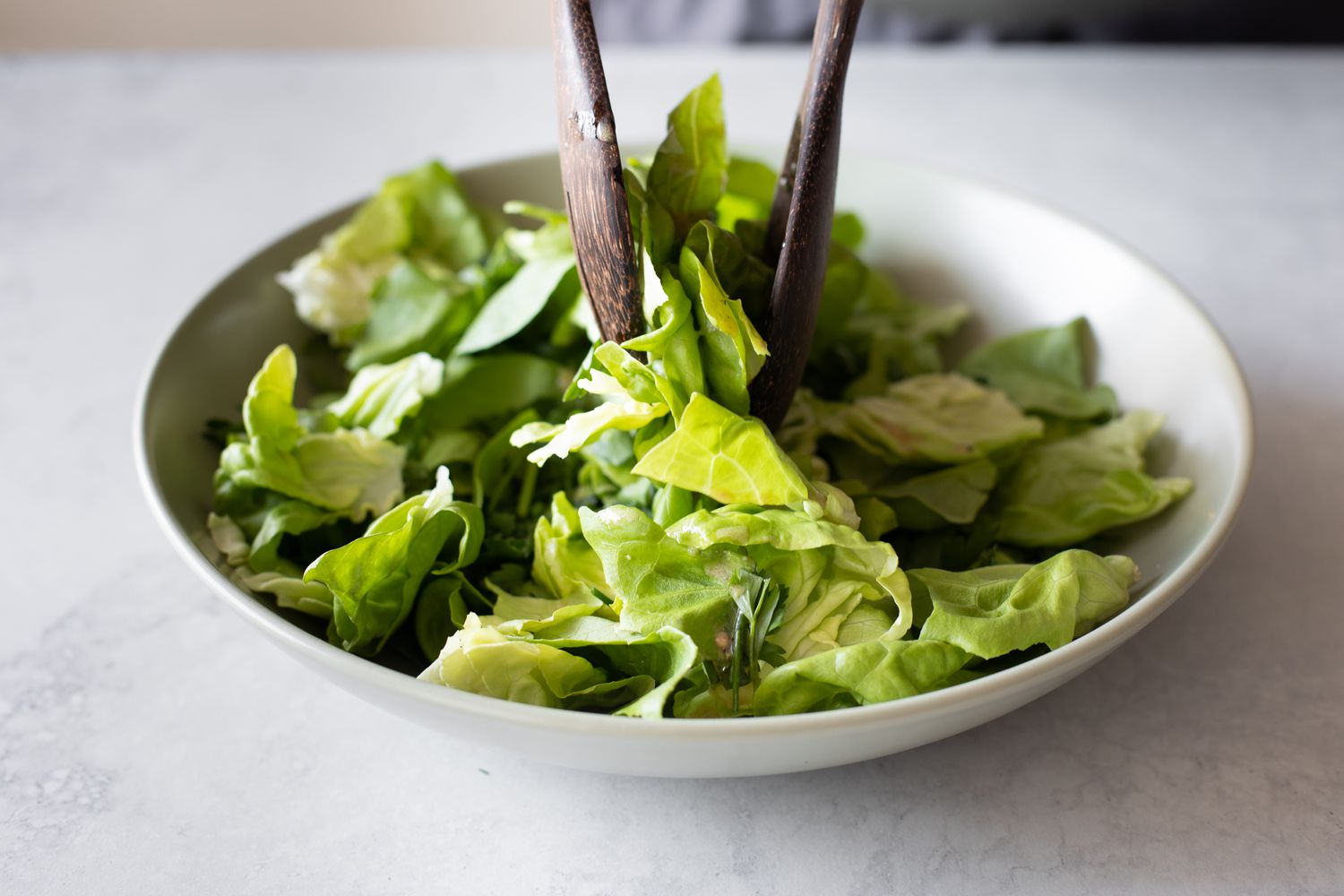 Bowl of Green Salad with Fresh Herbs and Red Wine Vinaigrette with Serving Utensils 
