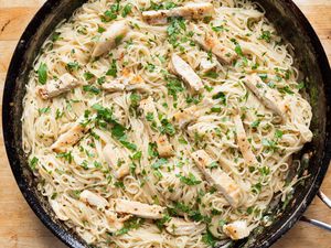 A pan of chicken scampi with pasta and herbs garnish