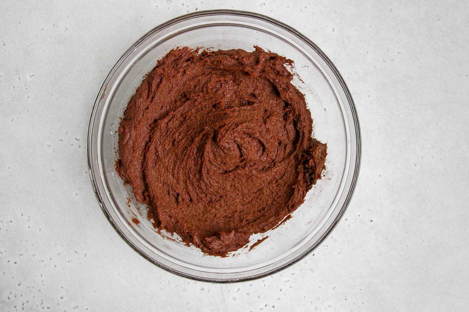 Chocolate dough in a glass bowl for chewy double chocolate cookie recipe.