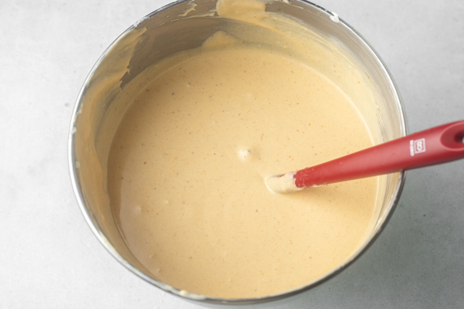 Making the feeling for pumpkin cheesecake in a metal bowl.