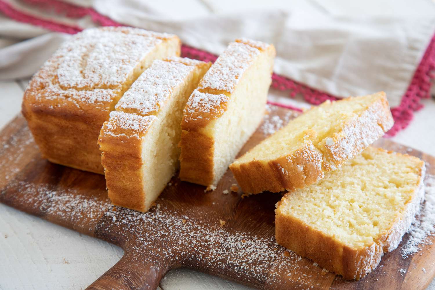 Side view of a sliced Simple Yogurt Cake on a wooden paddle.