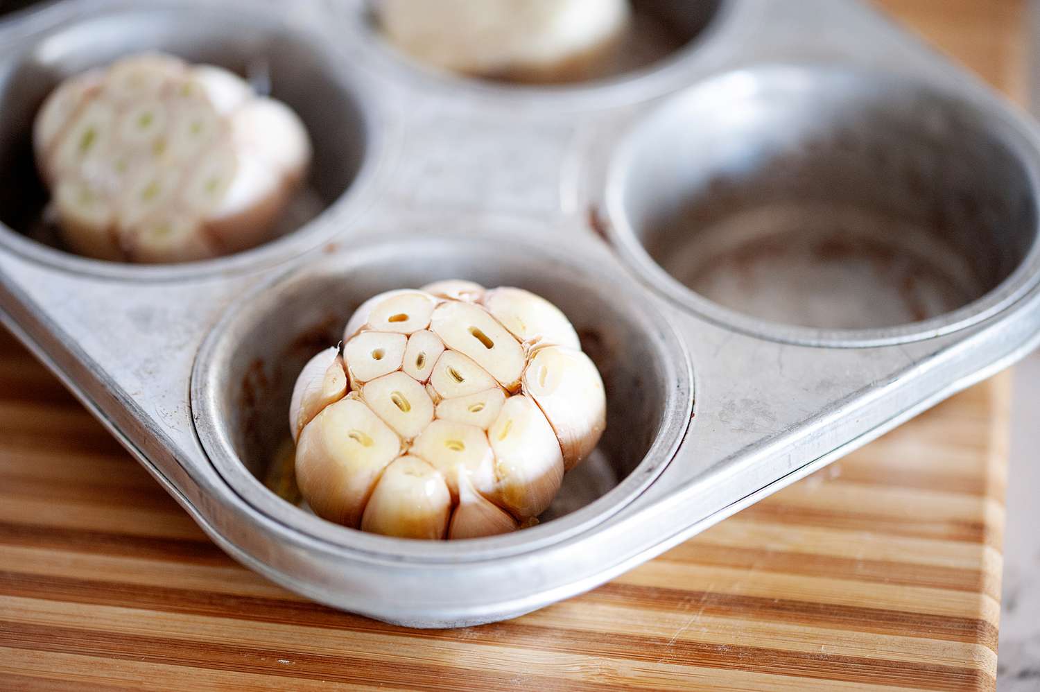 Fresh garlic with the cloves exposed set in a muffin tin.