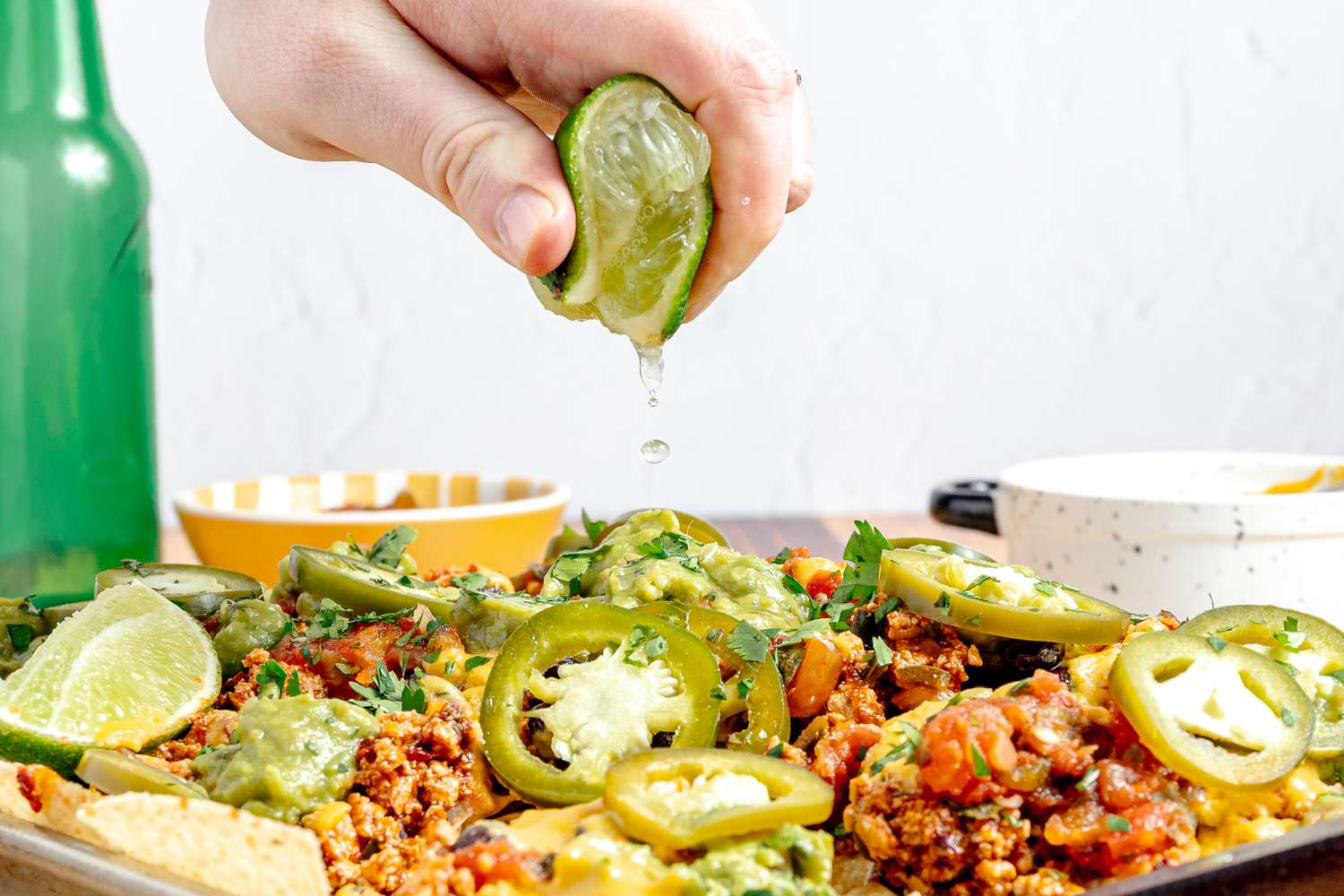 Slice of Lime Squeezed onto Baking Sheet of Vegan Nachos (Nachos Topped with Salsa, Queso, Pickled Jalpenos, and Two Lime Wedges) 
