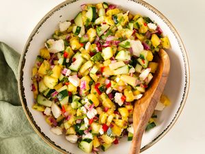 Pineapple Cucumber Salad with Feta in a serving bowl with a wooden spoon
