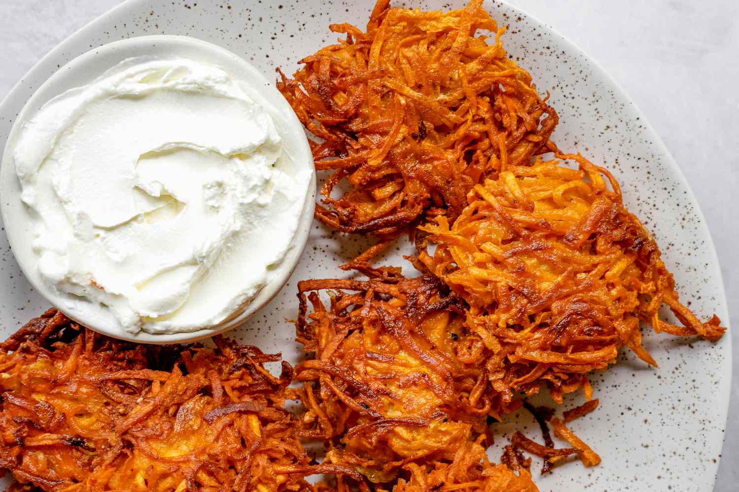 Plate of Sweet Potato Latkes Served with a Small Bowl of Sour Cream