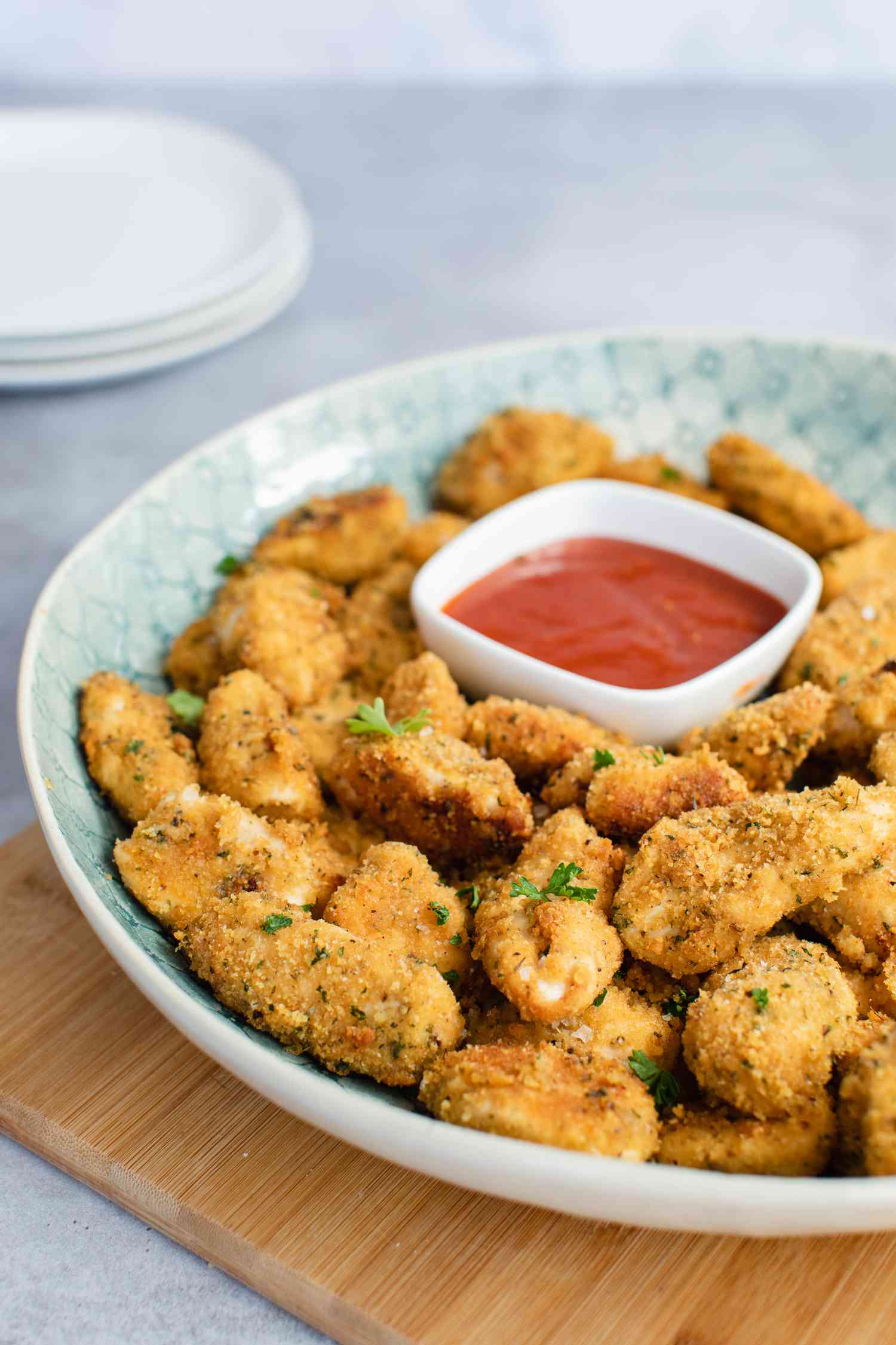 A serving tray with homemade chicken nuggets and ketchup on it.