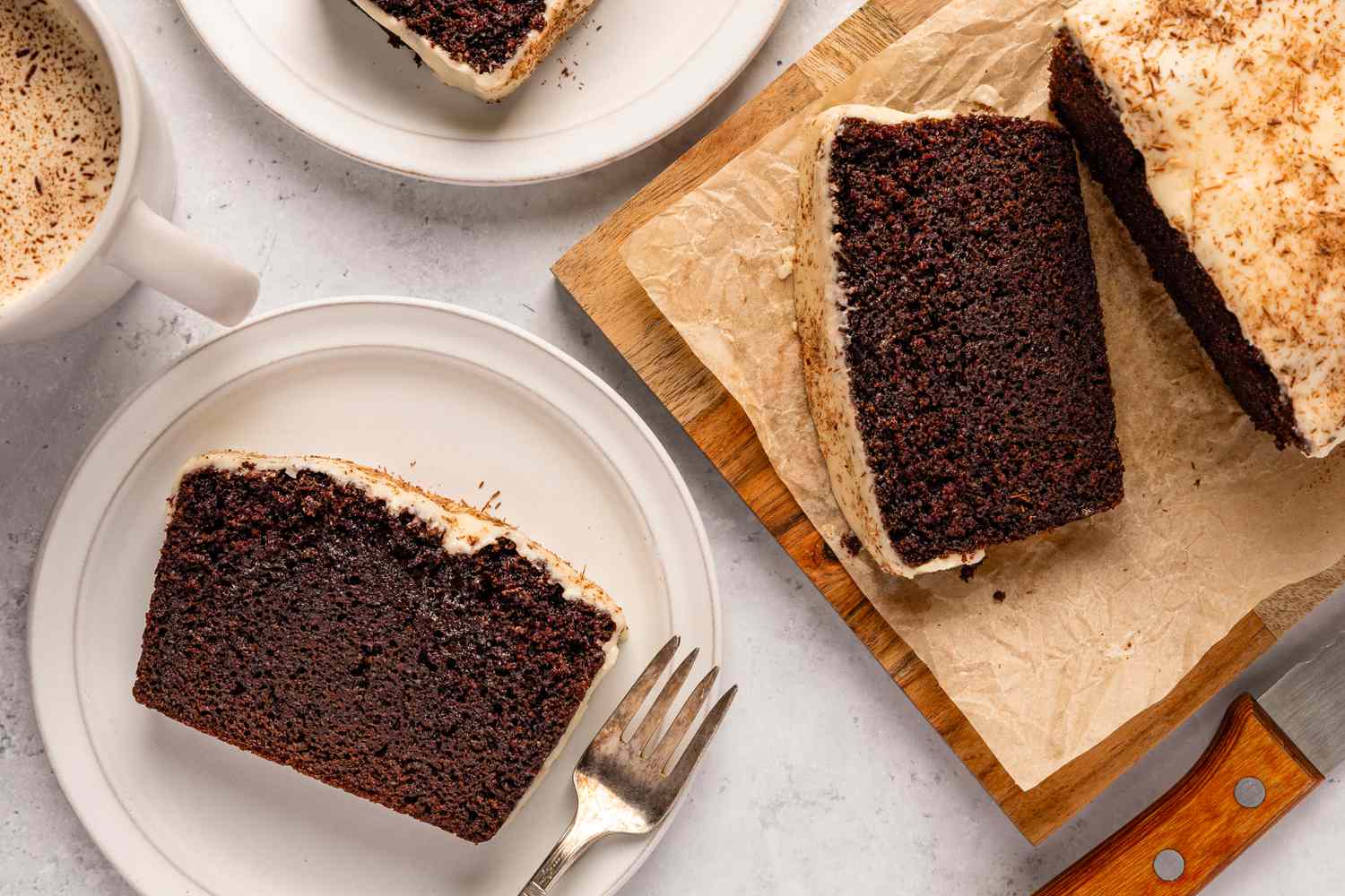 Overhead shot of a slice of chocolate stout loaf cake on a plate, next to the resto of the loaf on a wooden board