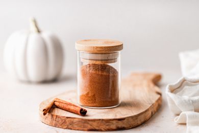 Homemade pumpkin pie spice blend in a jar on a wooden cutting board.