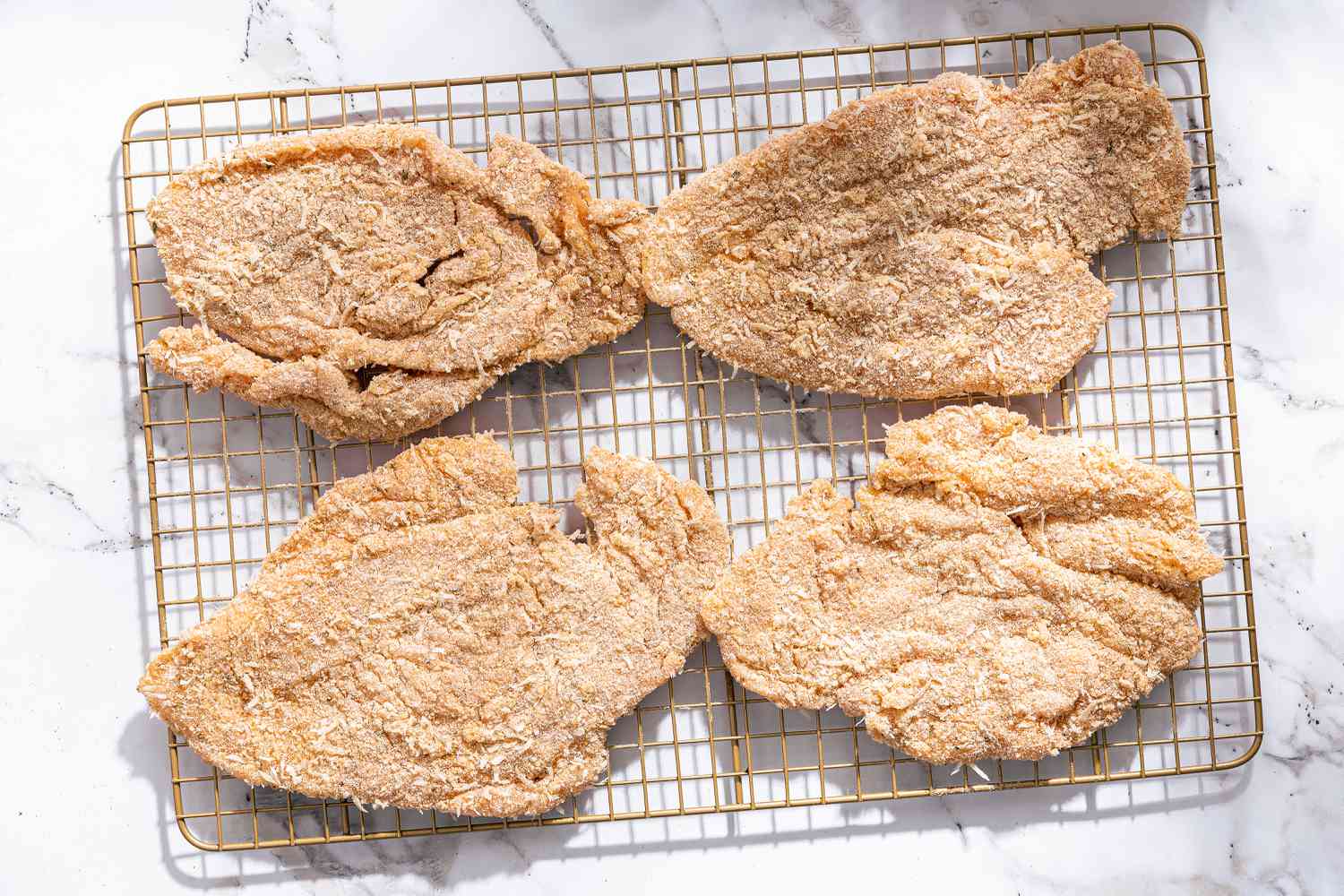 breaded chicken cutlets on a cooling rack for Chicken Romano