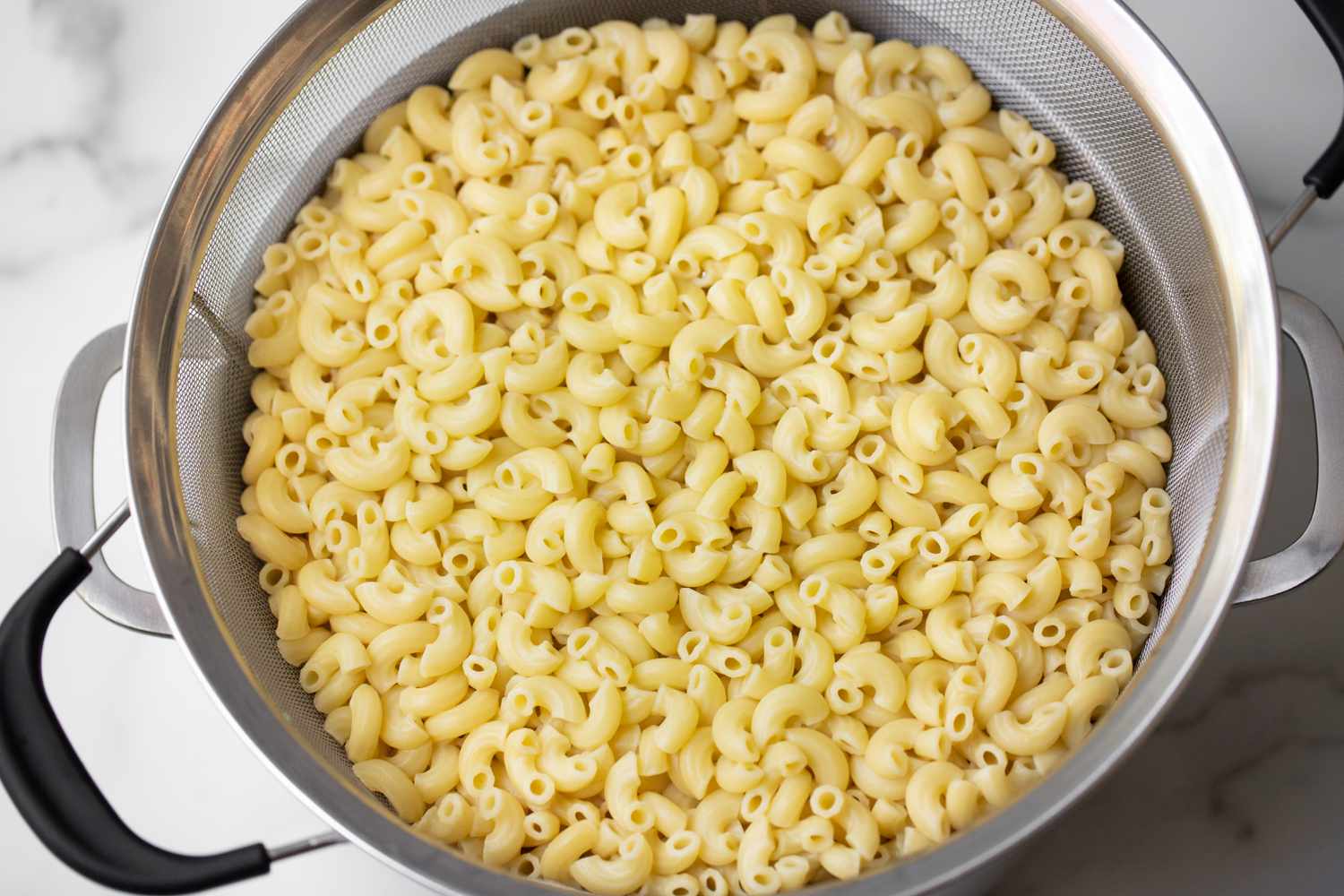 Cooked Elbow Macaroni in a Colander over a Pot for Trinidadian Macaroni Pie Recipe