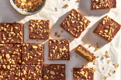 Oh Henry bars on a crinkled parchment paper with a bowl of crushed peanuts 