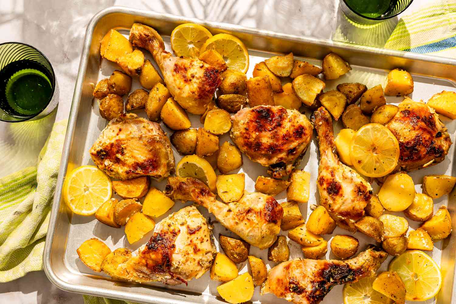 Greek-style chicken and potatoes with lemon slices on a baking sheet