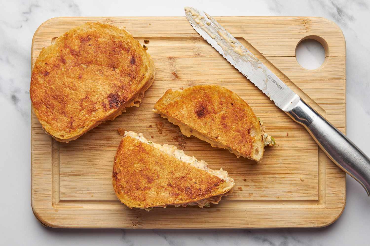 JalapeÃ±o popper grilled cheese sandwiches cut in half, diagonally on a cutting board