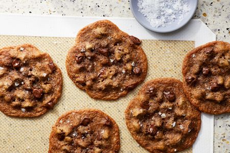 Chocolate chip cookies on a baking mat with a dish of salt nearby