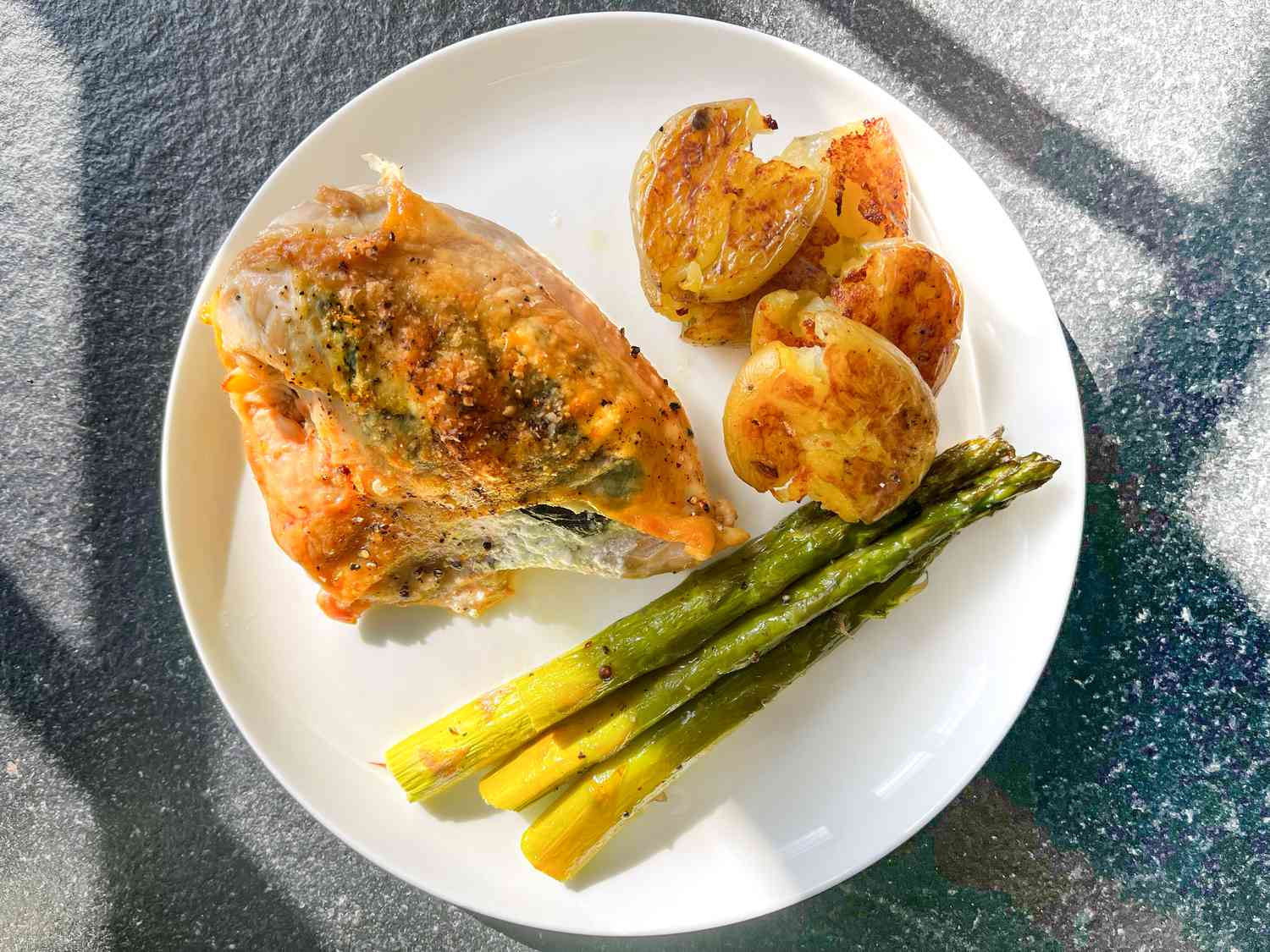 Roasted goat cheese chicken on a plate with potatoes and asparagus