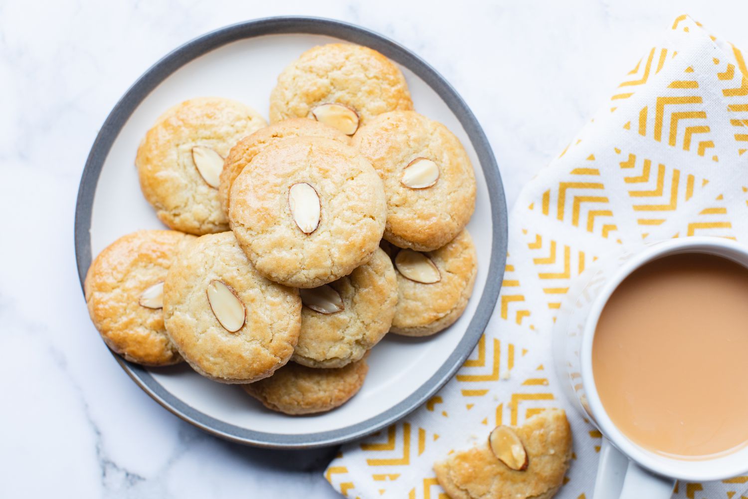 Overhead view of a plate of Chinese almond cookies and a mug.