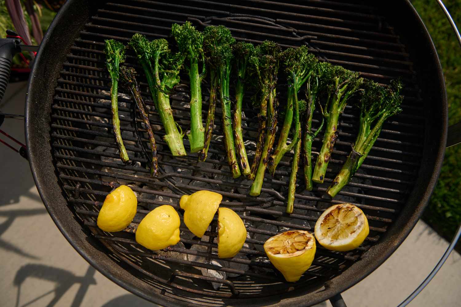 Broccolini and lemon halves cooking on a grill