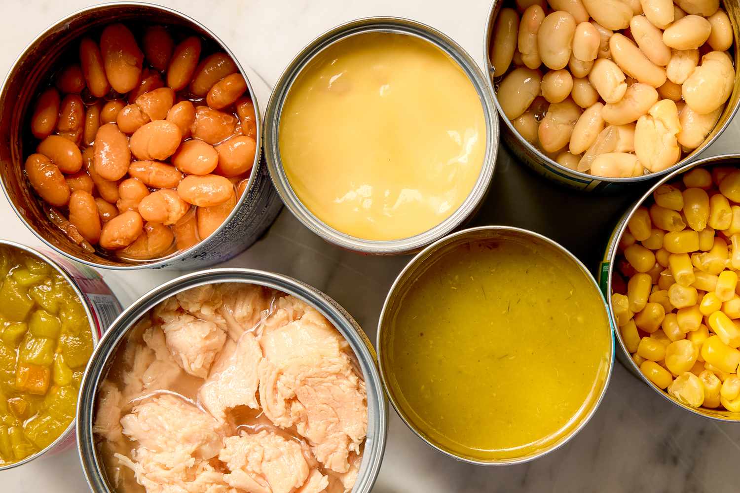 Ingredients for white chicken chili including beans chicken corn and broth in cans