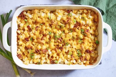 Baked casserole with diced ingredients melted cheese and garnished with green onions in a rectangular dish