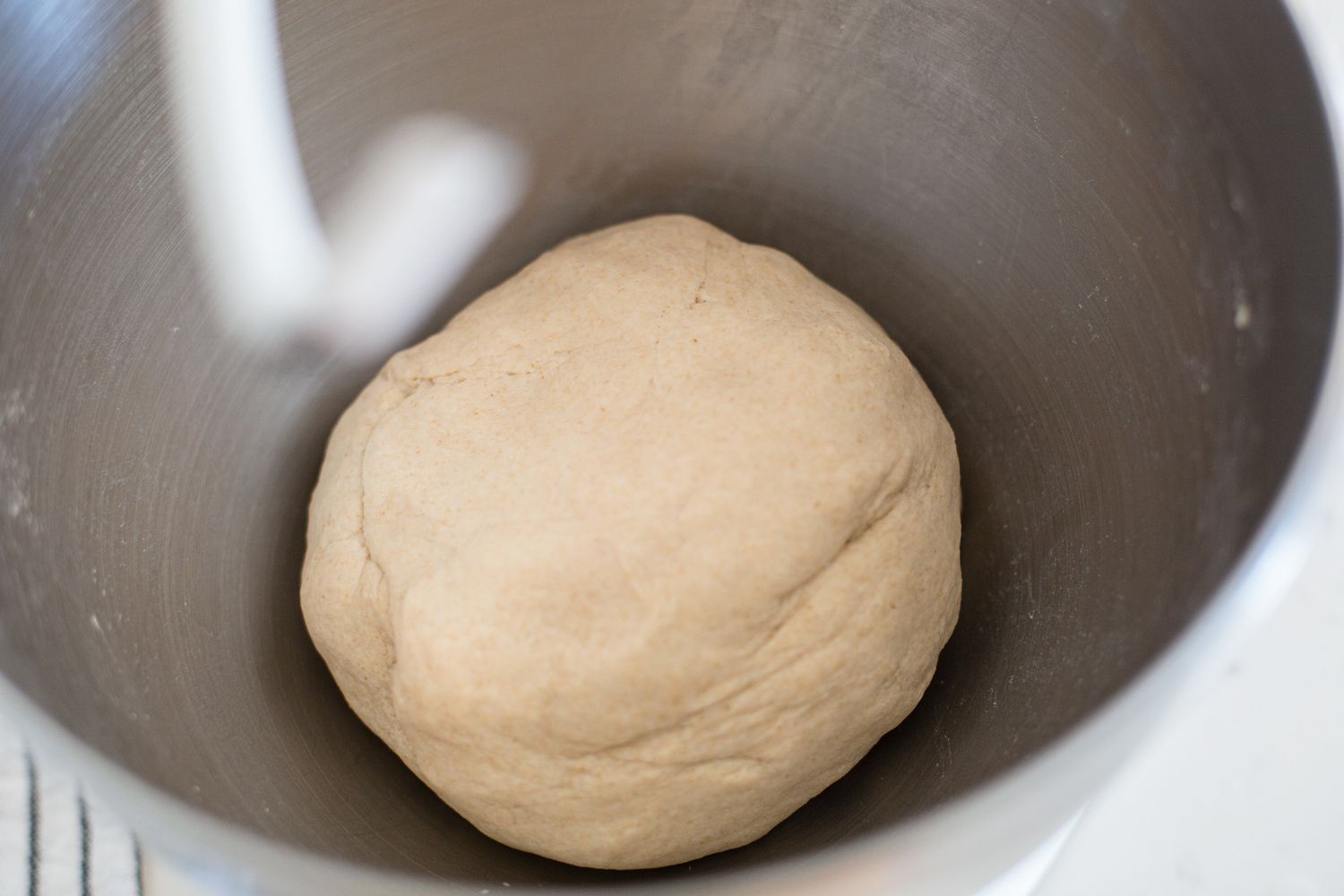 Kneading dough in a stand mixer to show how to make roti.