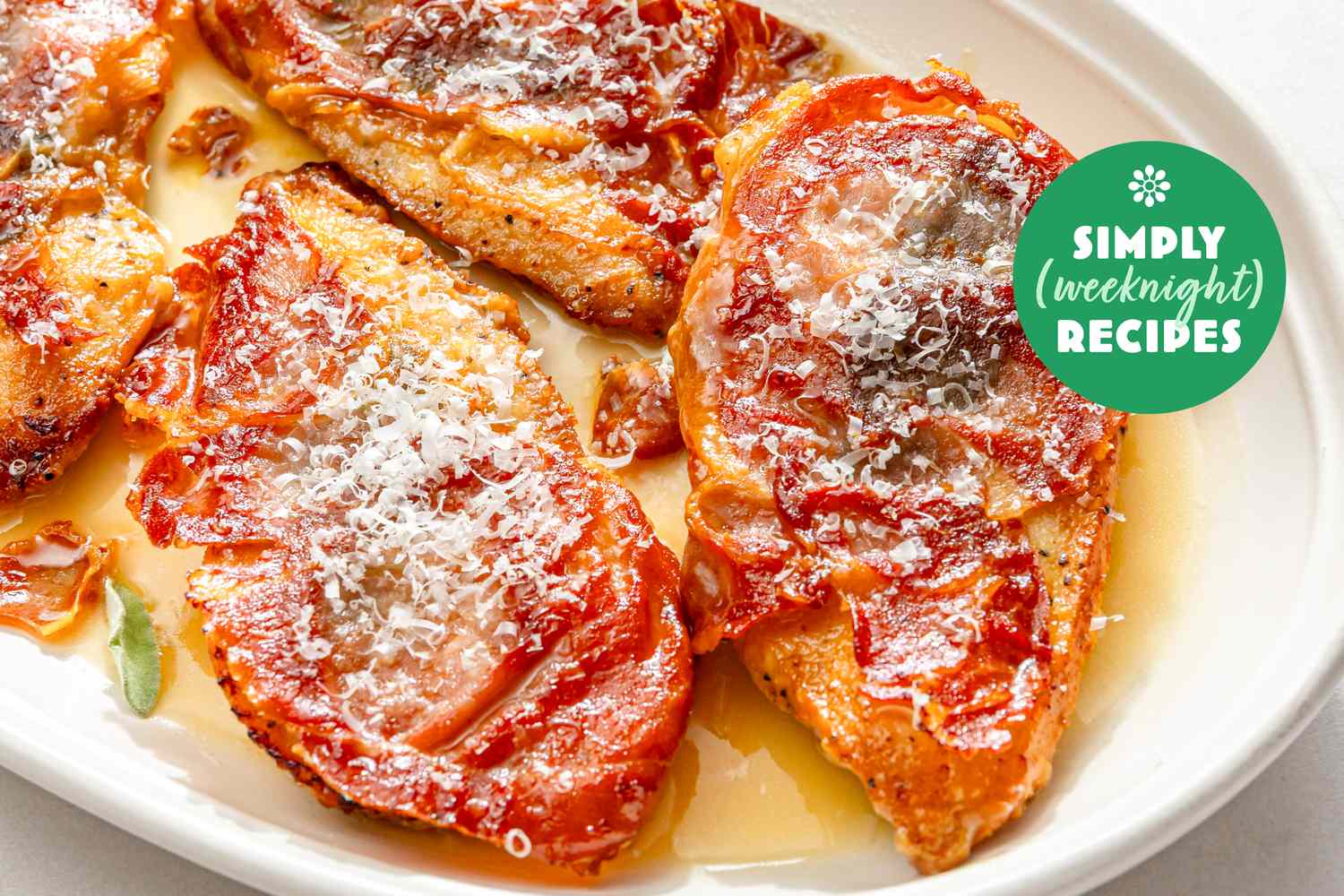 Chicken cutlets topped with tomato and cheese on a white plate with Simply Weeknight Recipes logo visible