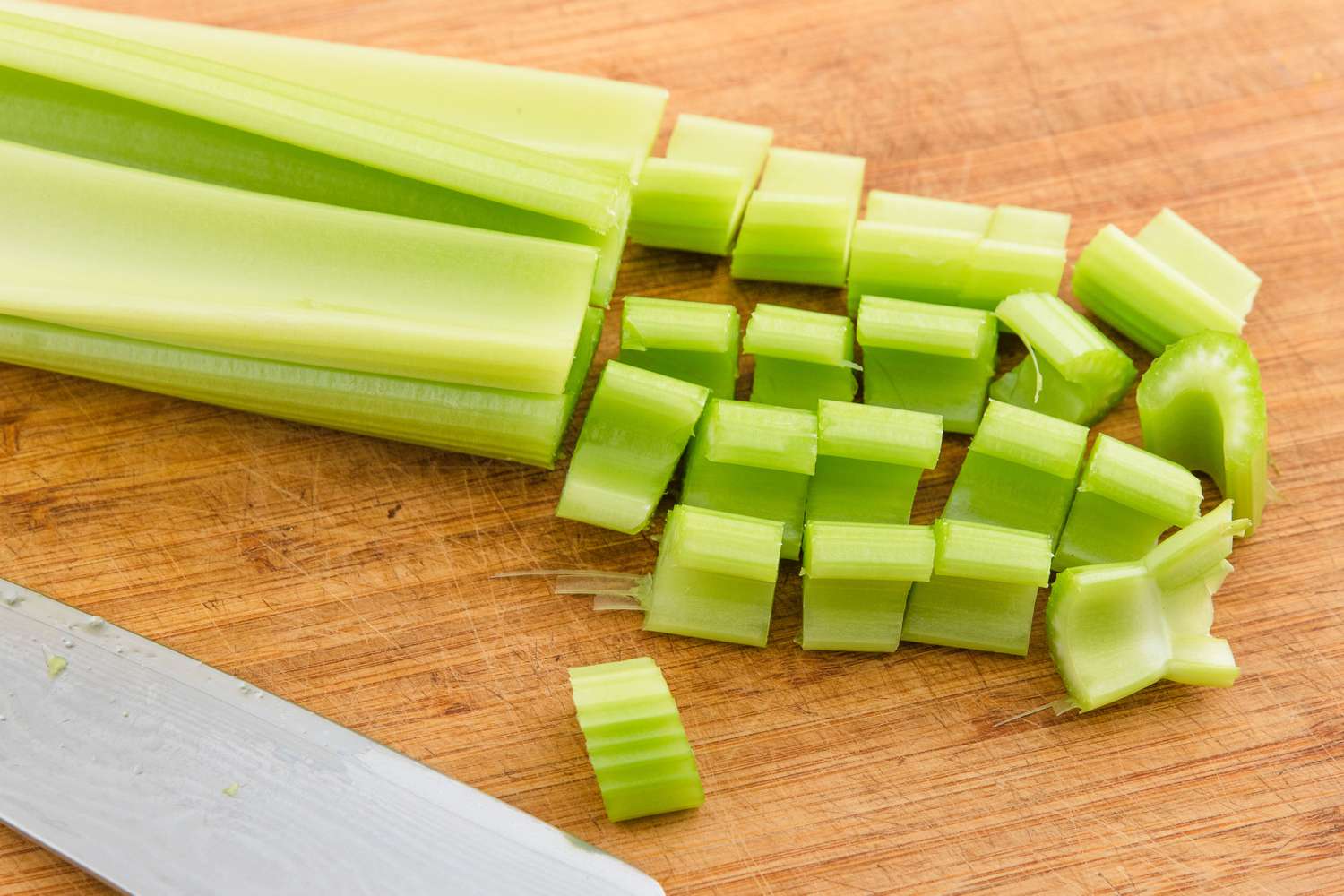 celery stalks, half chopped, on a cutting board with a knife