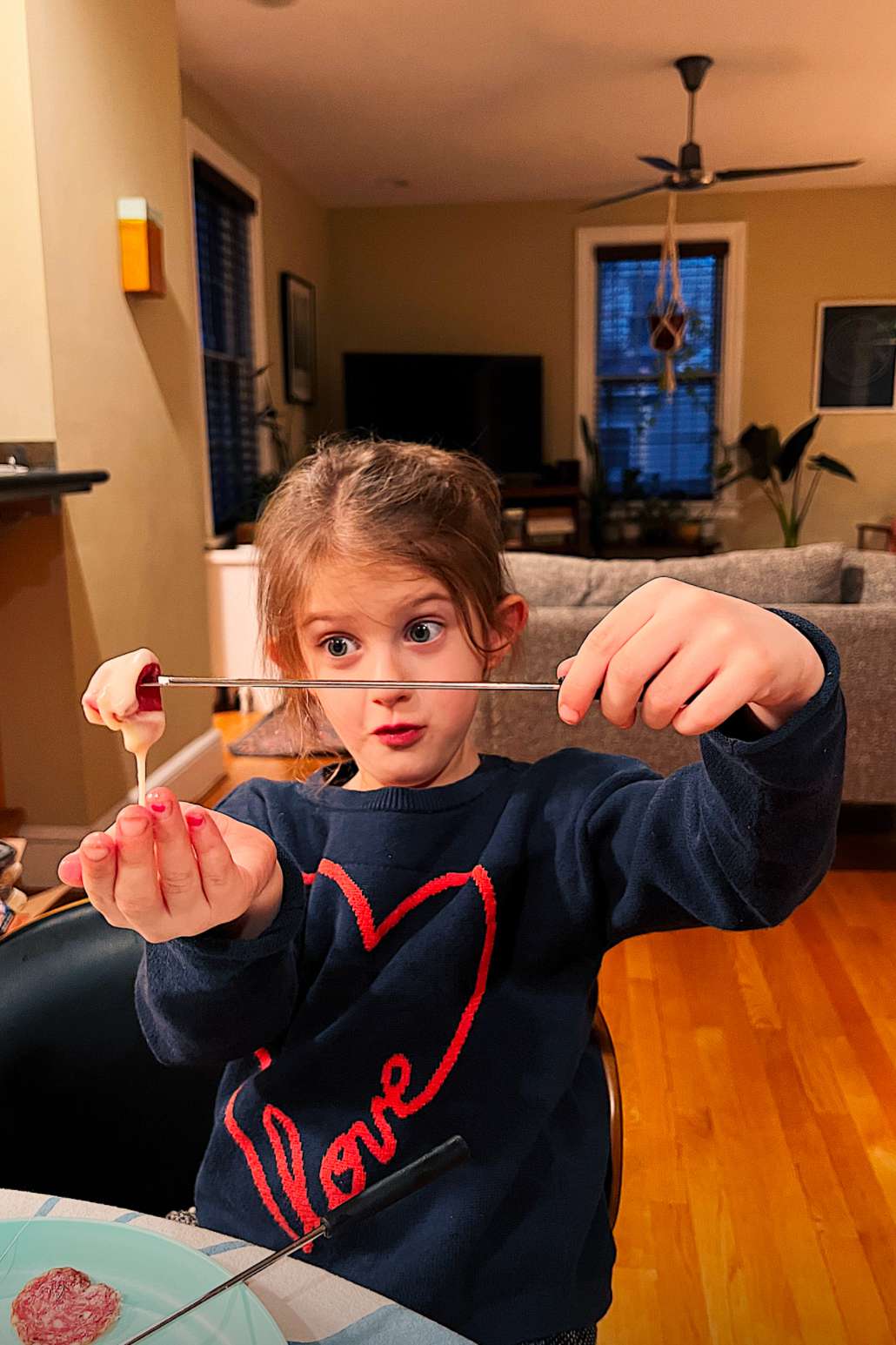 Girl holding a skewer of food that been dipped in cheese fondue