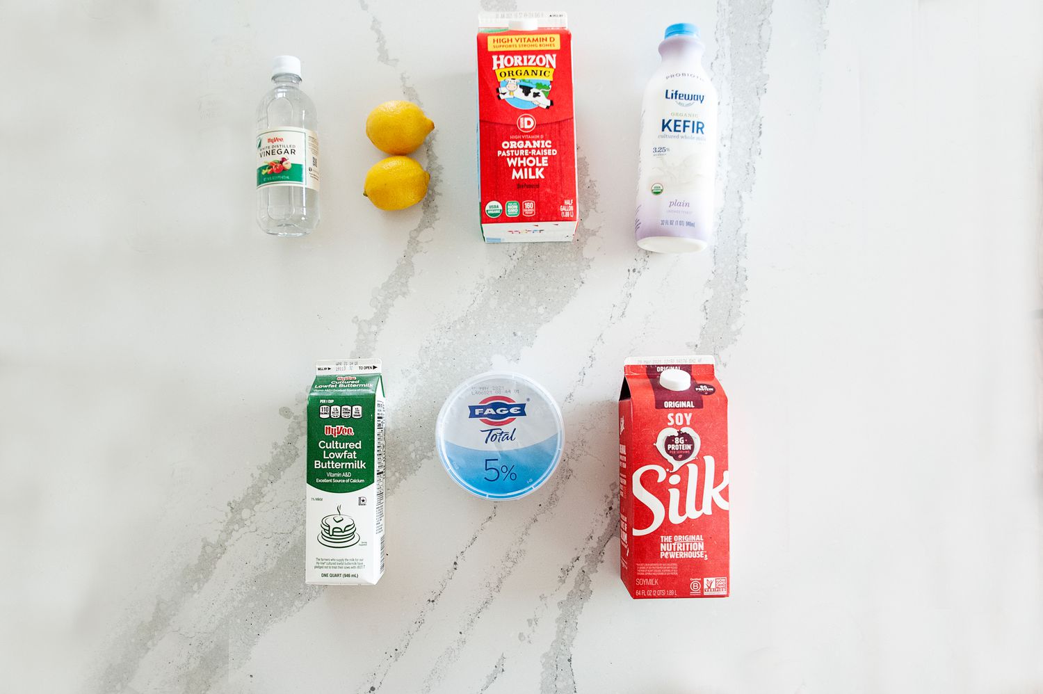 5 Buttermilk Substitutes laid on a colorful background.