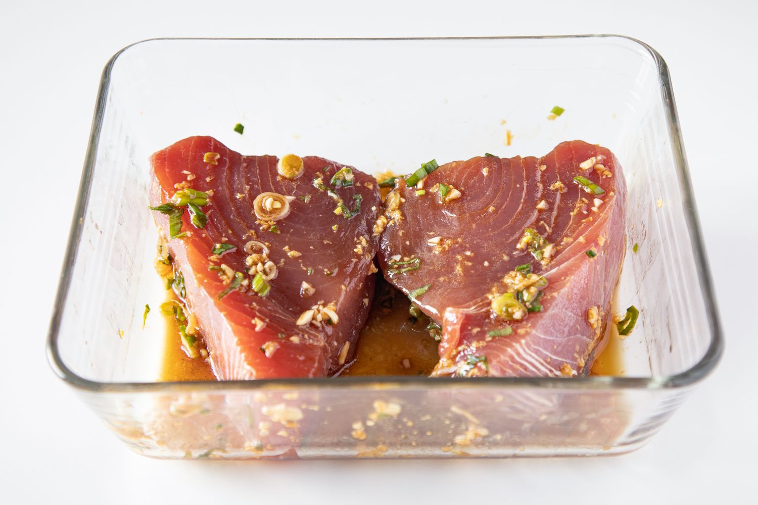 Marinating tuna steaks in a glass dish to make an ahi tuna steak recipe.