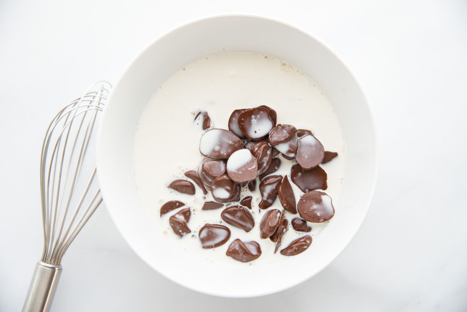 Chocolate chips in a bowl of heavy cream for a swiss roll cake recipe.