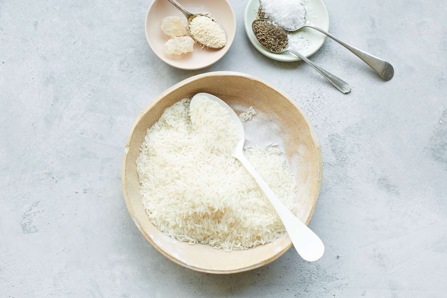 Washed Bowl of Rice in Bowl Next to Bowls of Seasoning for Chào Gá (Vietnamese Rice Porridge)