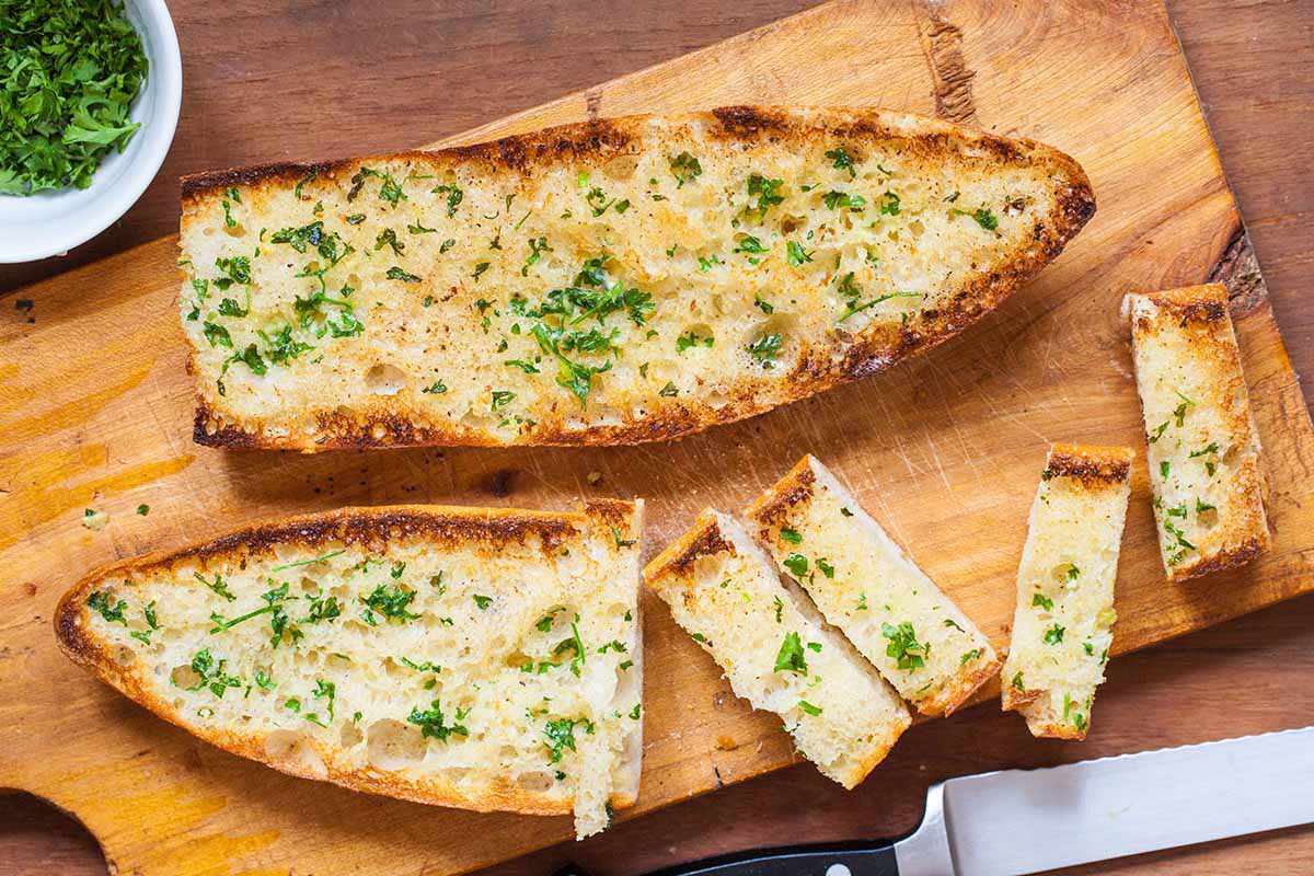 Homemade garlic bread cut into slices on a cutting board