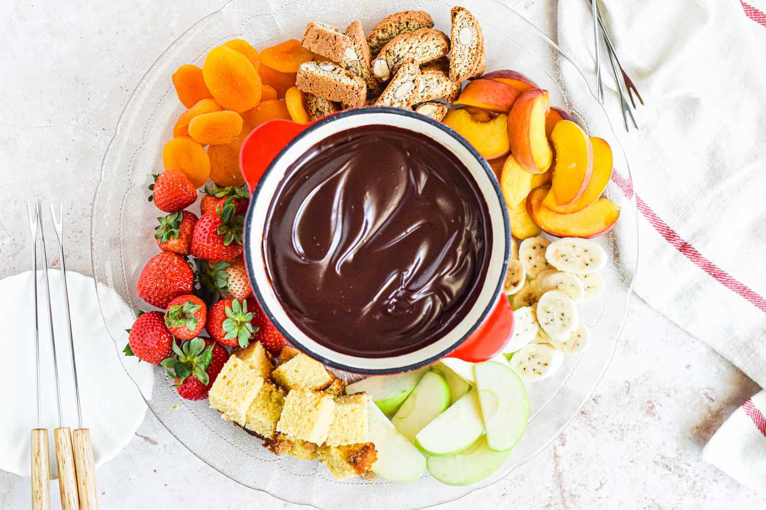Overhead view of chocolate fondue surrounded by sliced fruits.