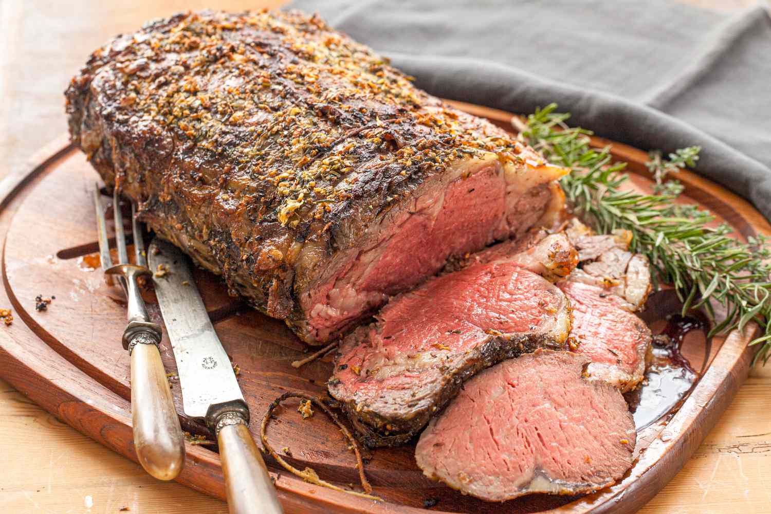 Herb butter prime rib with gravy being served on a cutting board.