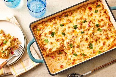 Overhead view of a teal baking dish with slice of King Ranch Chicken Casserole removed and on a plate to the side with a fork