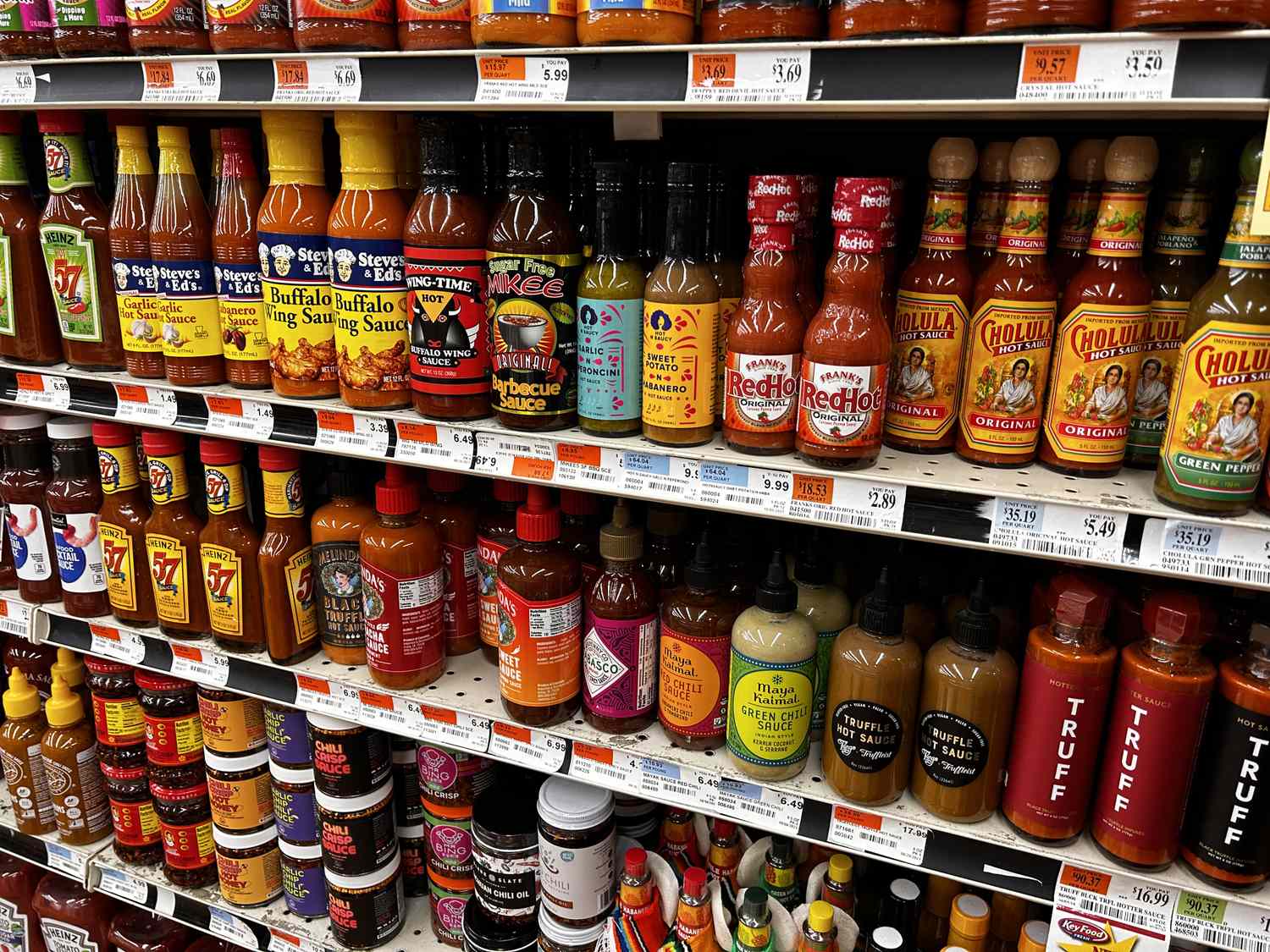 A grocery store shelf displaying a variety of hot sauce bottles