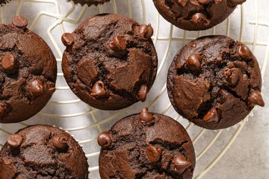 Chocolate muffins topped with chocolate chips cooling on a wire rack