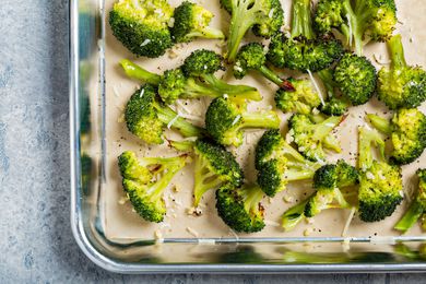 Broccoli florets sprinkled with grated cheese on a sheet pan