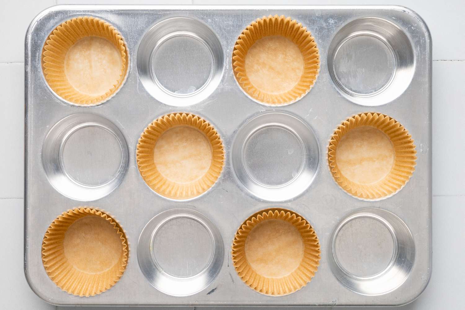 Muffin Wrappers Lining Every Other Divot in a Muffin Tin for Banana Chocolate Chip Muffins