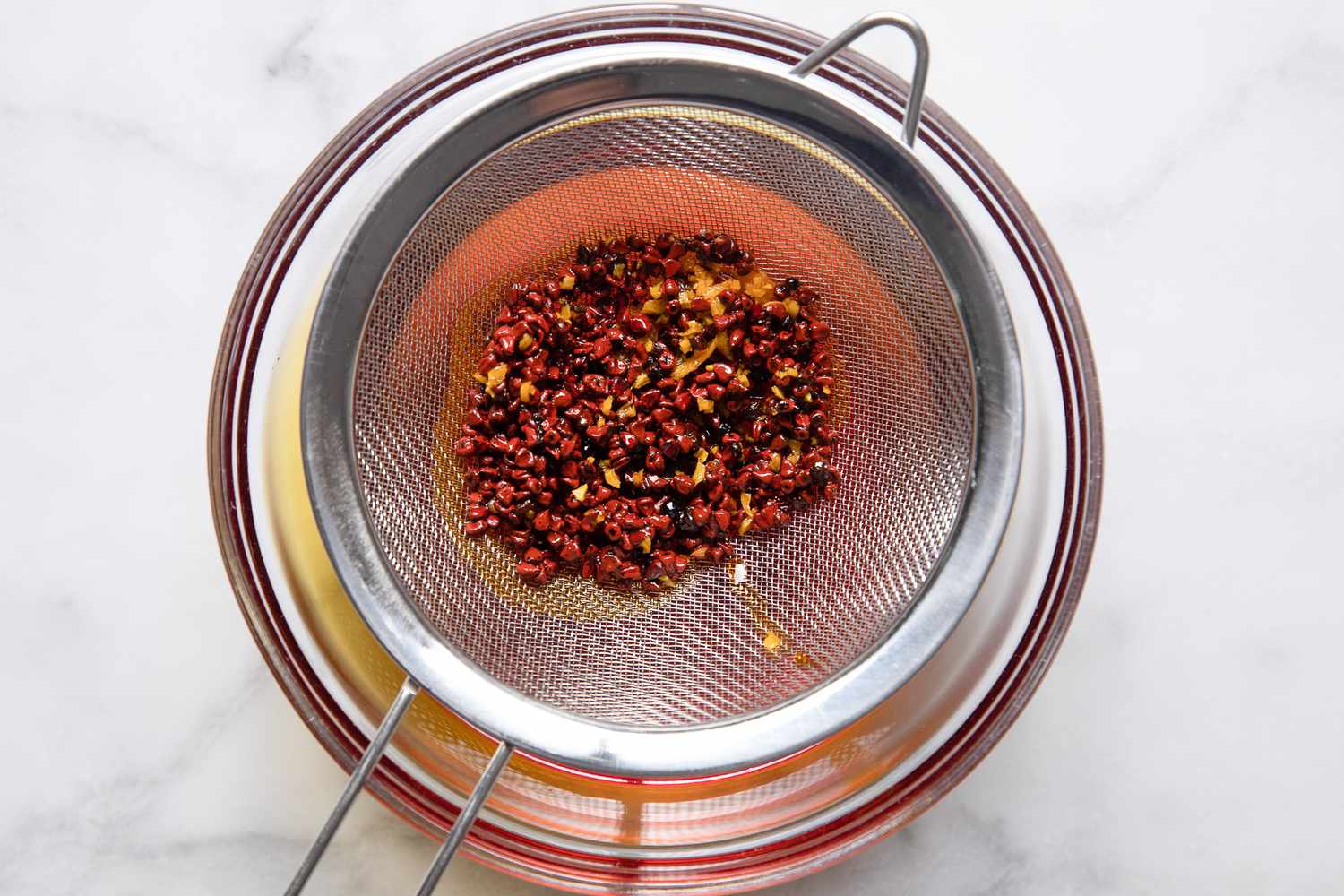 Annatto Oil Strained Through a Colander Over a Bowl for Banana Ketchup Recipe