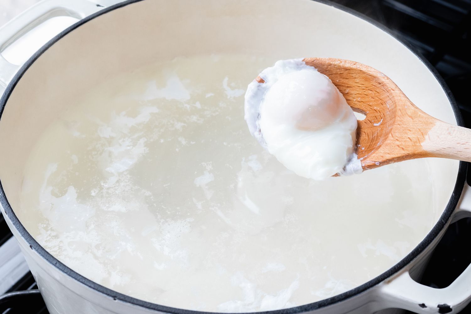 A Poached egg resting on a wooden spoon