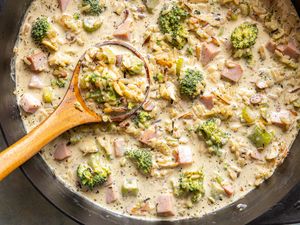 Broccoli and wild rice soup in a pot with a wooden ladle