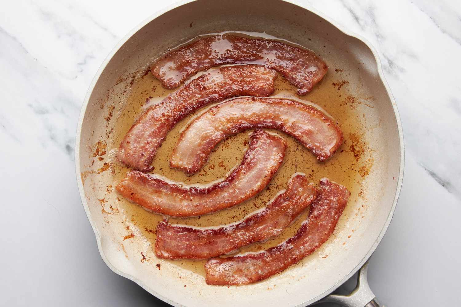 Bacon cooked on a skillet for jalapeÃ±o popper grilled cheese recipe