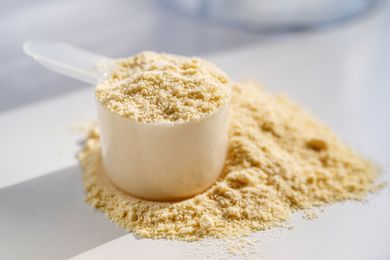 A scoop filled with protein powder with some powder spilled on a surface illustrating the ingredient
